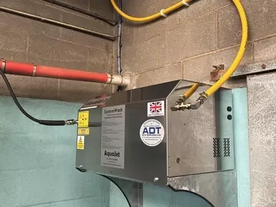 Stainless steel AquaJet 3 wall-mounted pressure washer installed at a dairy farm in Atherstone, raised for safety and protection.